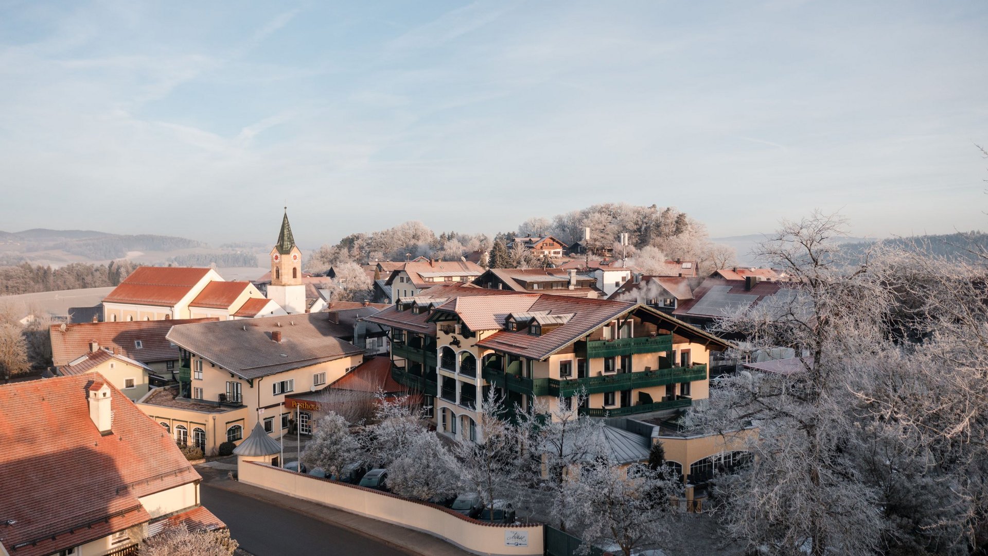 Ihr Wellnesshotel im Bayerischen Wald: Posthotel Rattenberg Verschneites Dorf mit Kirche und traditionellen Häusern an einem Wintermorgen